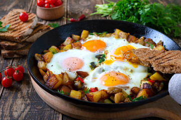 Fried eggs with vegetables  - shakshuka in a frying pan and rye bread on an old wooden background. Late breakfast. Rustic style. Middle eastern traditional dish