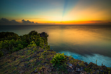 Fototapeta na wymiar Seascape. Spectacular view from Uluwatu cliff in Bali. Sunset time. Blue hour. Ocean with motion foam waves. Colorful sky. Nature concept. Soft focus. Slow shutter speed.