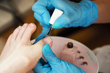 Process pedicure close up. Unrecognizable people. Master chiropody applying gel nail polish. Spa....