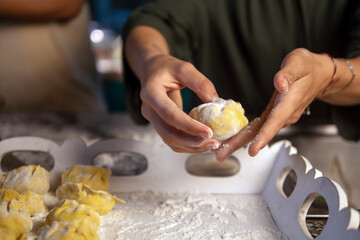 Female hands sculpt dumplings with meat over the kitchen table. Close-up of the hands of an adult woman with a slice of minced meat and dough. The process of making homemade meat dumplings. Homemade