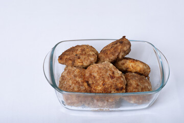 Meat cutlets in glass plate or container isolated on white background, close-up, copy space