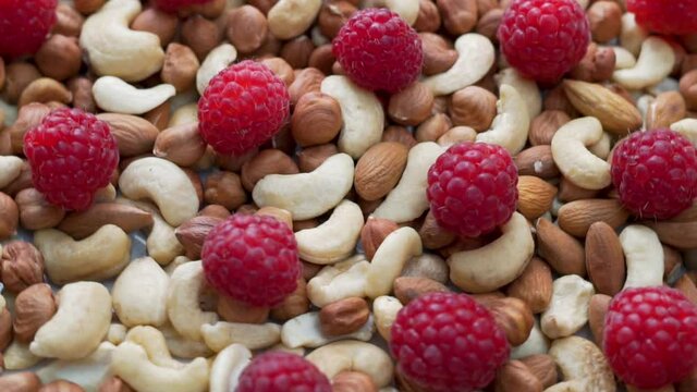 Healthy Dish with Healthy Hazelnuts Cashews Almonds and Raspberries. Nuts and Raspberries Rotate, Isolated. Background of Nuts and Raspberries. The Concept of a Healthy Proper Vegan Diet.  