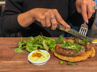 Female hands eating breaded grilled meat or burger with a tasty fresh salad and golden baked french fries, showing a upper level healthy fast food alternative.
