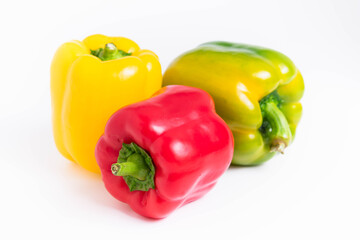isolate, three ripe peppers of red, yellow, green colors, close-up on a white background