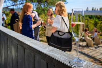 Glass of white sparkling wine with raspberries on a gray fence