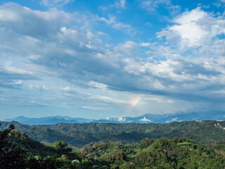 Rural rainbow landscape, view of green meadows and mountains