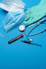 Top view of Medical equipment and tools on blue background - stethoscope, surgical mask, medical gloves, syringe and test tube - healthcare and medicine concept. Medical banner design