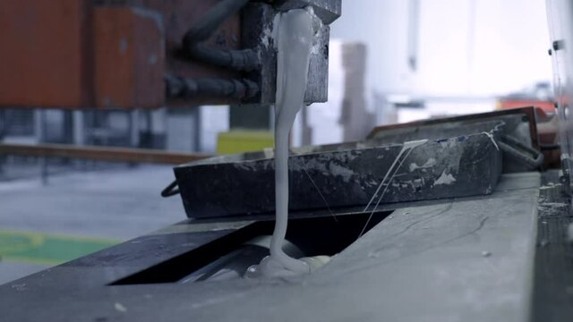 White paint is poured into a bucket, the process of manufacturing paint in the factories, the process of colorization in the factory. Close up industrial video shot.