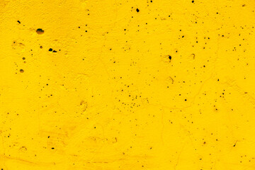 Yellow concrete wall with dots and cracks