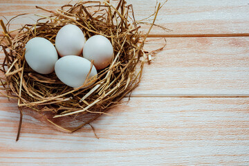 White eggs in hay nest on wooden table background