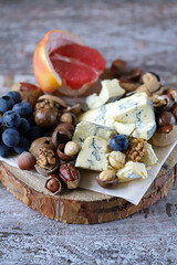 Selective focus. Cheese, nuts and fruits. Cheese snack on a wooden stand. Wine appetizer.
