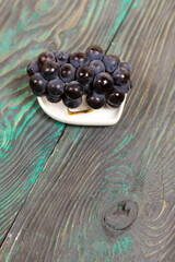 A bunch of dark blue grapes. Lies on black-green pine boards.