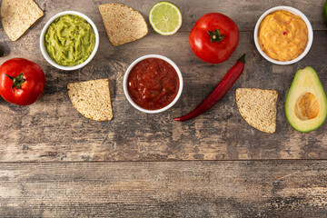 Traditional Mexican sauces. Guacamole, chilli pepper sauce and cheese sauce on wooden table