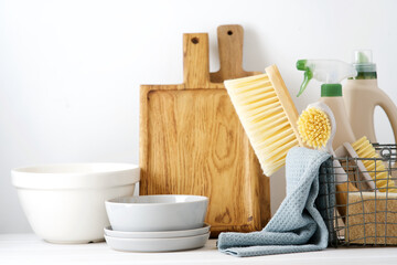 Eco brushes, sponges and rag in the basket. Dish washing detergents. Cleaner concept on white...