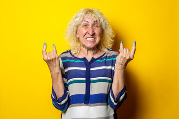 Blond old woman in striped dress shows goat jet, rocker goat on a yellow background