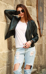 Young girl in trendy retro 90s style leather jacket and jeans on street of old city