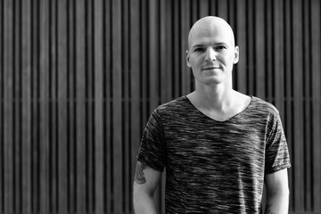 Young handsome bald man against wooden gate
