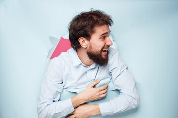 Emotional bearded man peeks out from behind the wall in office work shirt