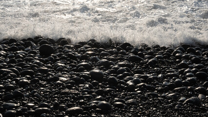 Waves on the shore of a black pebble beach