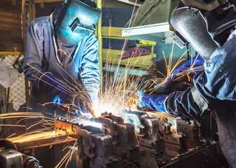 Teamwork worker with protective mask welding metal.