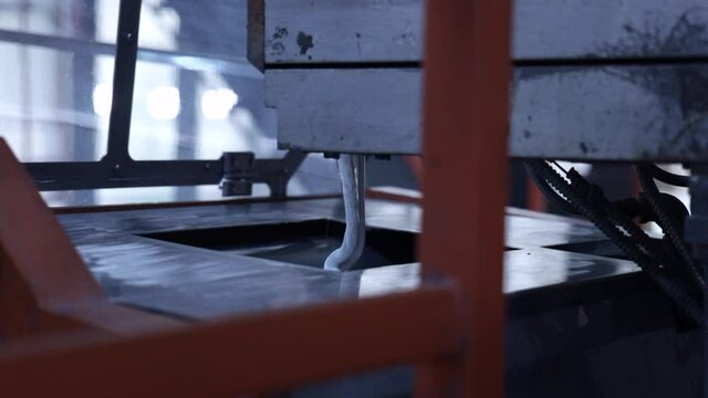White paint is poured into a bucket, the process of manufacturing paint in the factories, the process of colorization in the factory. Close up, sliding, slow motion industrial video shot.