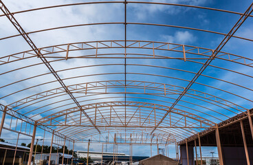 Details of steel roof frame with blue sky and clouds.