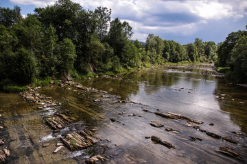 San river in the Bieszczady Mountains in Poland. Clear water and interesting rock formations at the bottom of the river. Shores surrounded by green vegetation