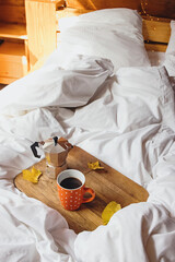 Cup of coffee on wooden tray on the comfort bed.