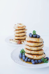Stack of homemade small thick pancakes served with fresh blueberries.