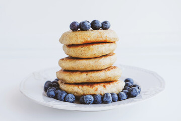 Stack of homemade small thick pancakes served with fresh blueberries.