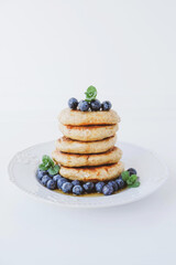 Stack of homemade small thick pancakes served with fresh blueberries.