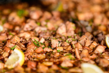 Large group of cooked mussels with tomato and cream sauce at a street food festival, ready to eat seafood,  beautiful orange monochrome outdoor background.