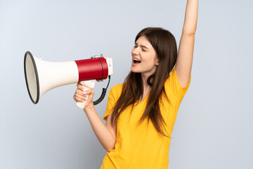Young Ukrainian girl isolated on white background shouting through a megaphone to announce...