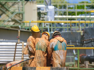 A man is working to drill a pipe in a sloppy industrial factory.