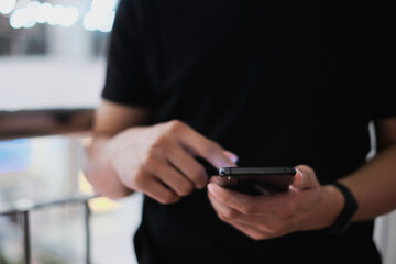 Closeup of male hand holding modern smartphone, man's hand using cellphone at night city, bokeh...