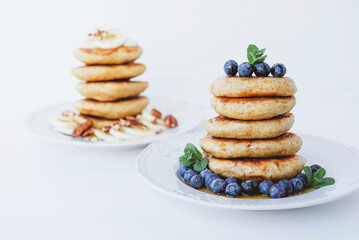 Stack of homemade small thick pancakes served with fresh blueberries.