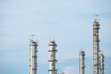 Close up and up-view shot with copy space of tall towers made of metal and stainless steel for refining oil and petrochemical production shows the symbol of pollution and environment problem growth.
