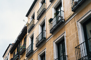 Fototapeta na wymiar Low angle view of traditional cast iron balconies of old residential building in Lavapies quarter in central Madrid