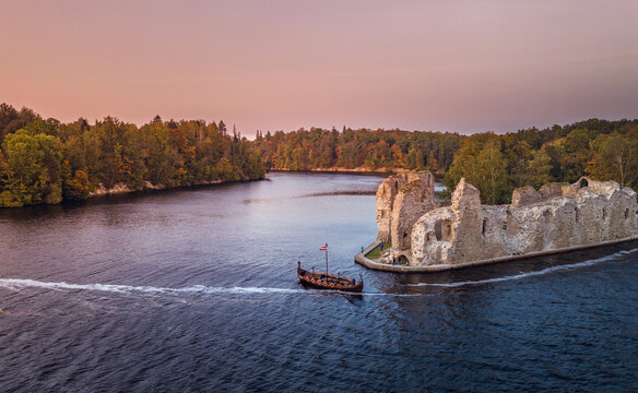 Aerial view of Koknese castle ruins at colorful sunset. Medieval ruins on the shore of river surrounded by forest.  