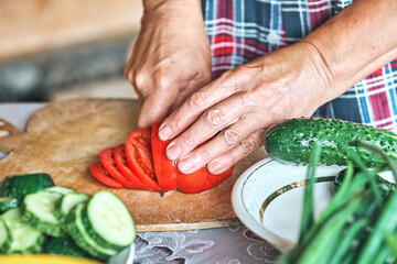 Close-up of female hands cutting vegetables for salad