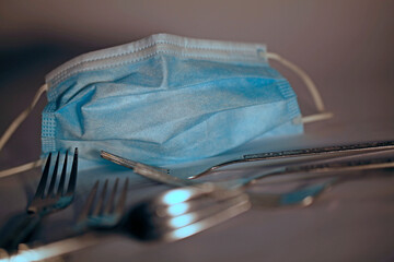 Un masque de protection bleu pour le virus corona ou le virus Covid-19 et des fourchettes pour la...