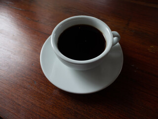 White coffee cup with black coffee placed on the wooden table