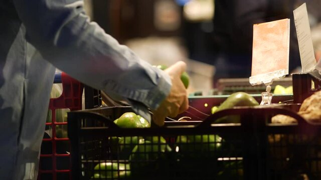 Senior Female Shopper Selects Green Peppers In A Supermarket. An Elderly Woman Takes A Sweet Bell Pepper With Her Hand And Puts It In A Cart. Paprika Is Sold At The Grocery Store