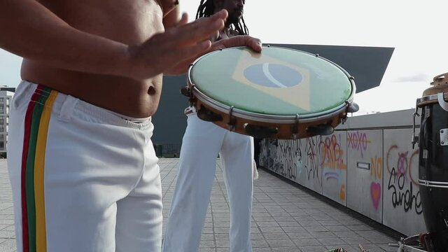 Capoeira artist playing the tambourine or pandeiro musical instrument.