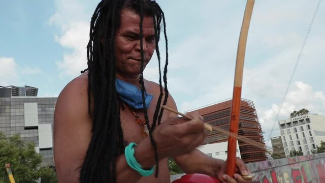 Brazilian Rastaman musician playing the Berimbau instrument with a bow.
