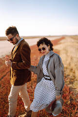 Young loving couple walking and hugging in autumn field. Enjoying time together. Fashion, lifestyle and autumn mood.