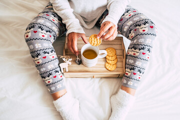 View of caucasian woman at home doing breakfast on the bed in winter season - christmas pants and...