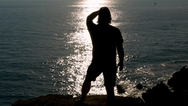Silueta de hombre vigilando el horizonte en un acantilado frente al reflejo del sol en el mar un d&iacute;a sensacional. Desde Conil, C&aacute;diz, Andaluc&iacute;a, Espa&ntilde;a, Europa.