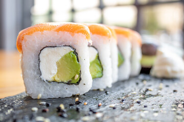 sushi roll filled with avocado, cream cheese and salmon topping