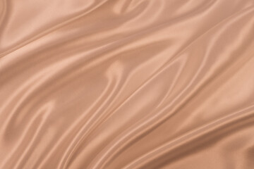Photography of beautiful elegant wavy beige / light brown satin silk luxury cloth fabric texture, abstract background design. Copy space. Card or banner